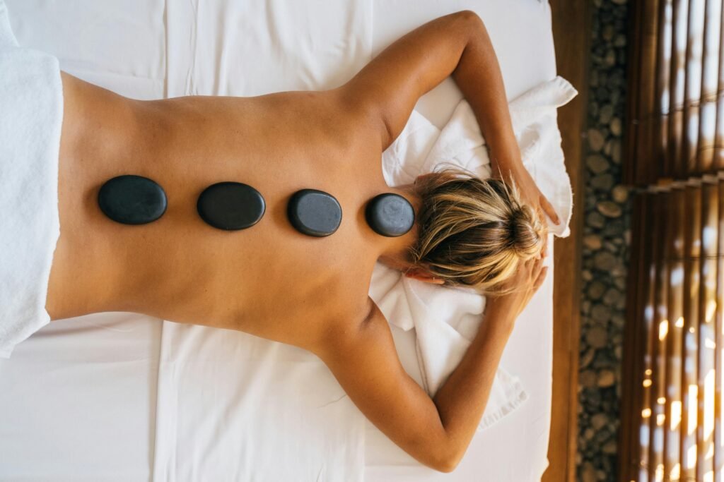 pexels-photo-6560266-6560266 A serene hot stone massage therapy session with smooth black stones placed on the back for relaxation.